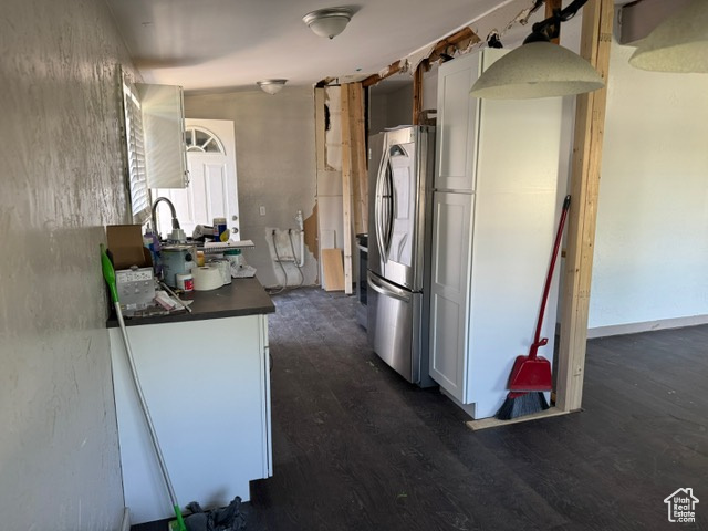 Kitchen with freestanding refrigerator, dark countertops, dark wood-type flooring, and white cabinetry