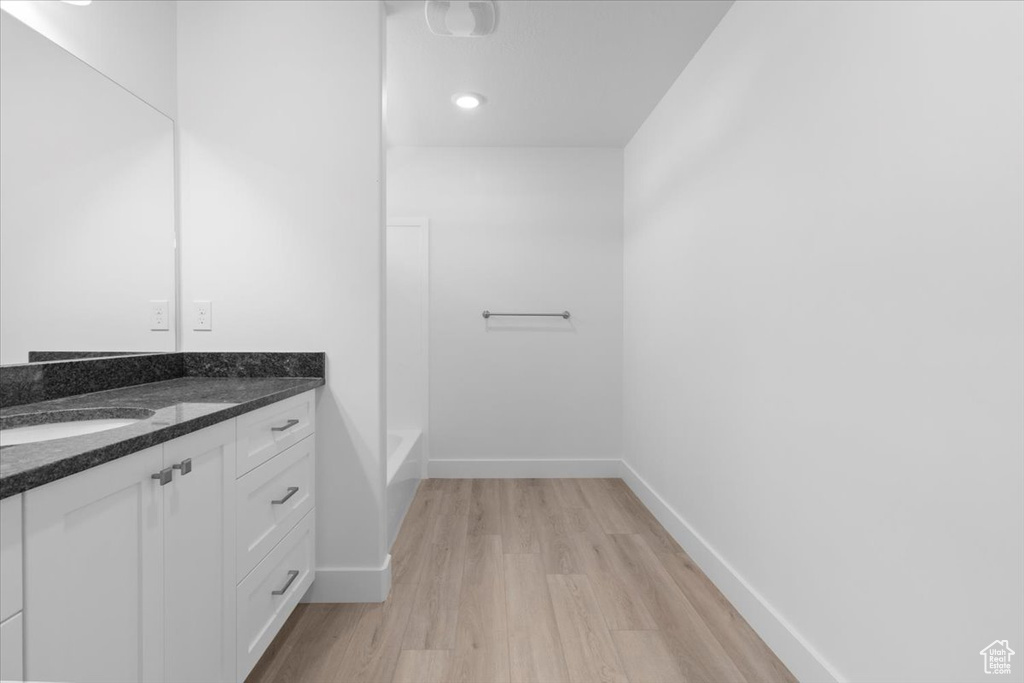 Full bathroom with vanity, wood finished floors, and a bathtub