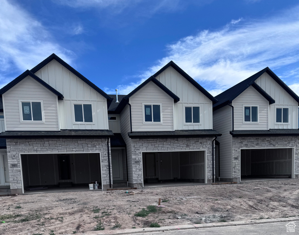 View of front of home featuring board and batten siding, an attached garage, and stone siding