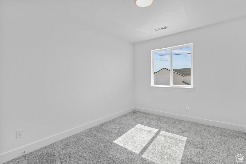 Carpeted spare room featuring baseboards