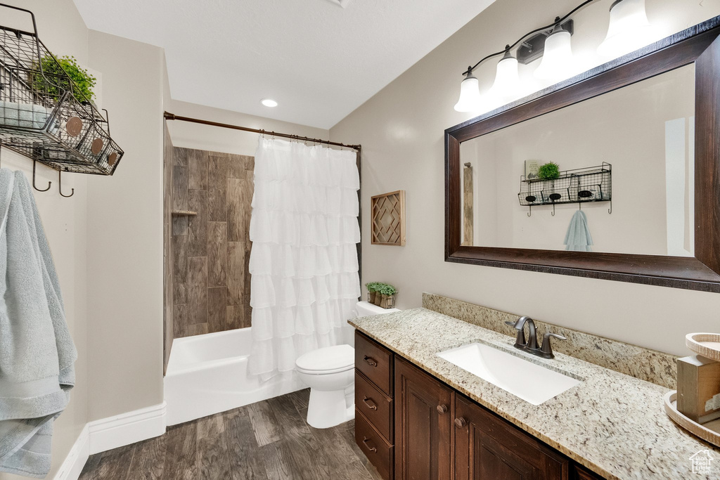 Full bathroom with vanity, wood finished floors, shower / bath combination with curtain, and recessed lighting
