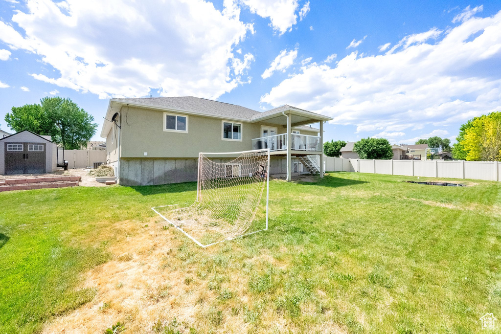 Rear view of property with stairway, a storage unit, a fenced backyard, and a deck