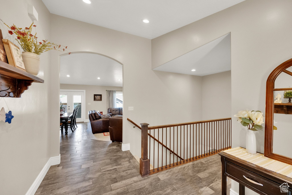 Hall with arched walkways, an upstairs landing, recessed lighting, and wood finished floors