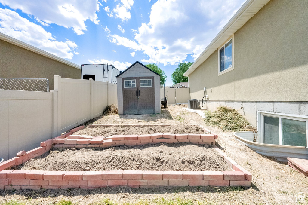 Fenced backyard featuring a storage unit