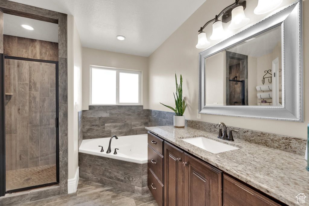 Full bath with vanity, a bath, and a stall shower