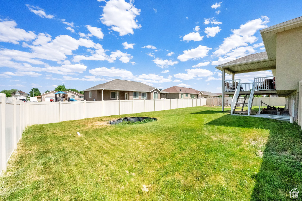 Fenced backyard with stairs, a residential view, and a wooden deck