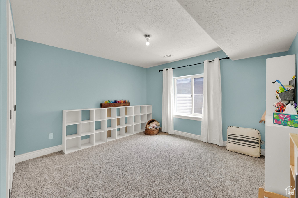 Playroom with carpet flooring and a textured ceiling