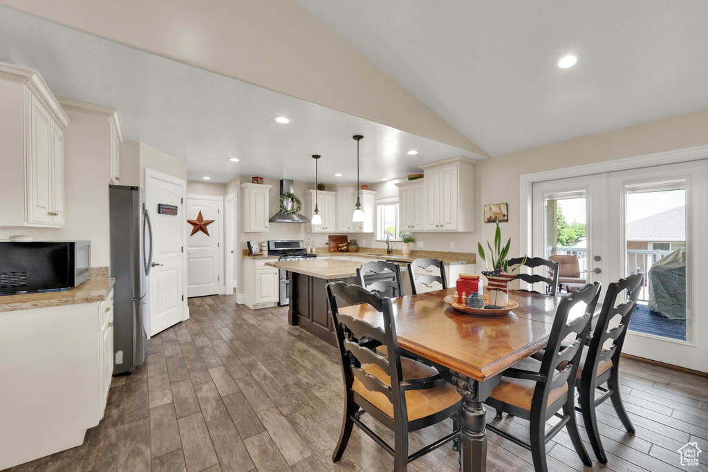Dining room with wood finished floors, lofted ceiling, recessed lighting, and french doors