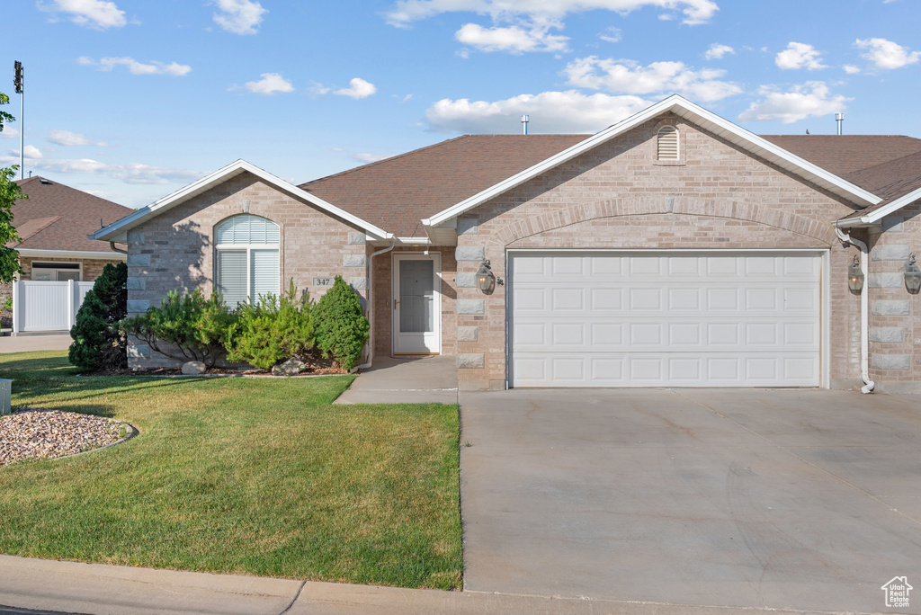 Ranch-style home featuring driveway, brick siding, a front yard, an attached garage, and a shingled roof