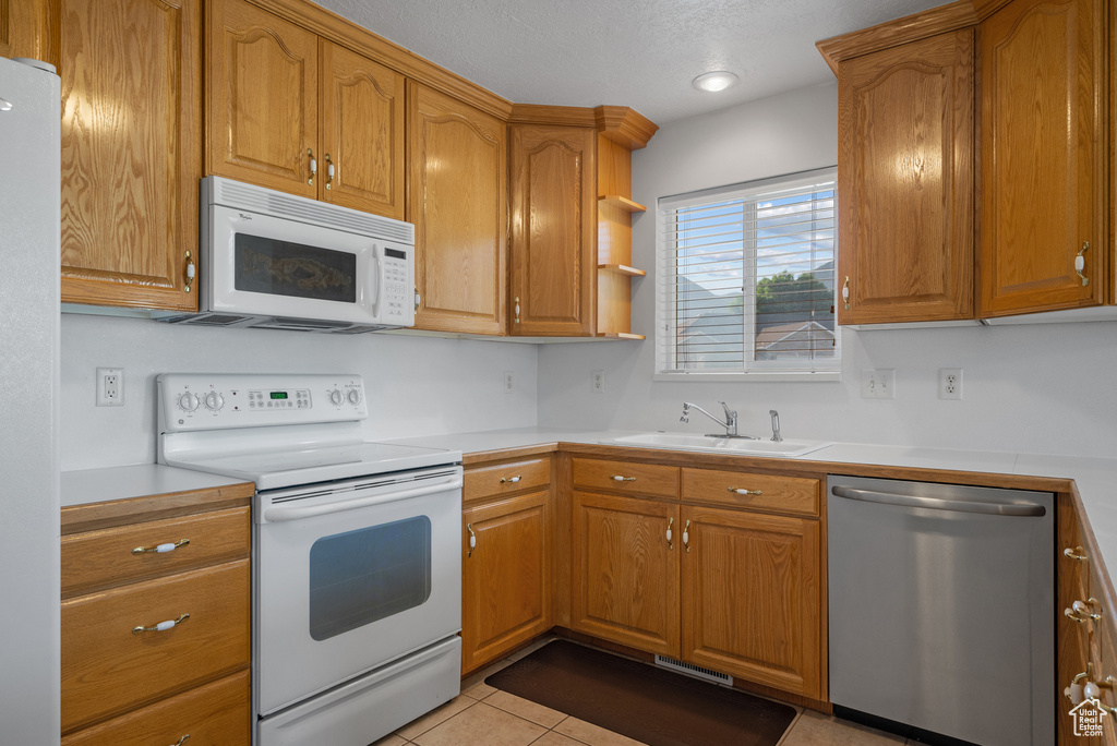Kitchen with white appliances, light countertops, and brown cabinetry