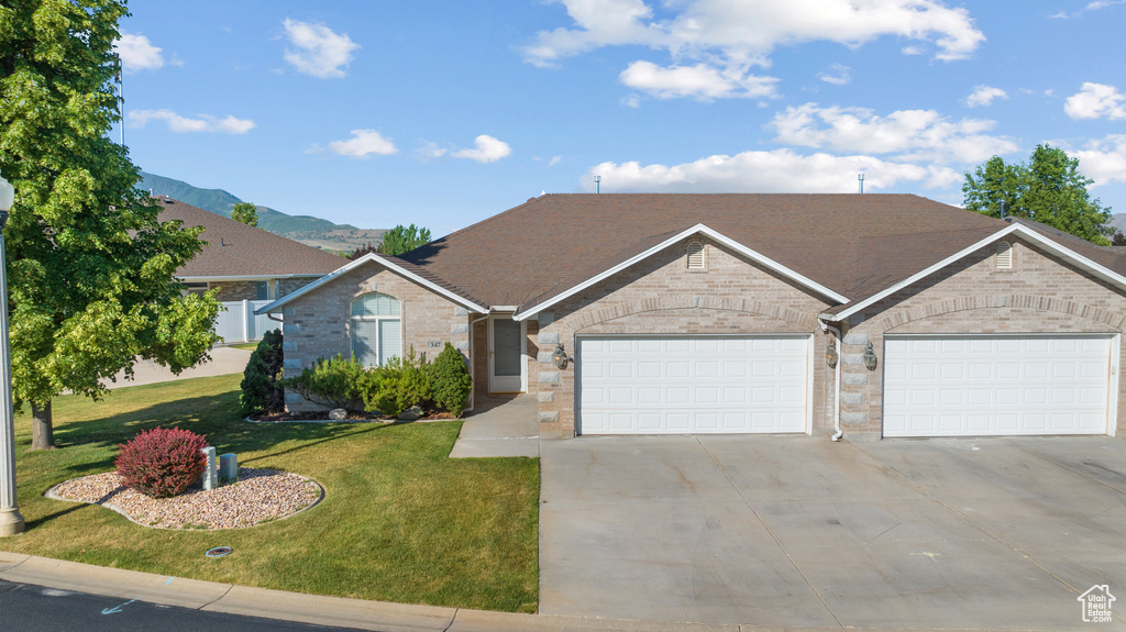 Ranch-style home with driveway, a garage, a front lawn, brick siding, and roof with shingles