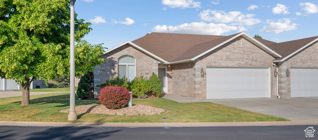 Ranch-style home with an attached garage, brick siding, concrete driveway, and a front lawn