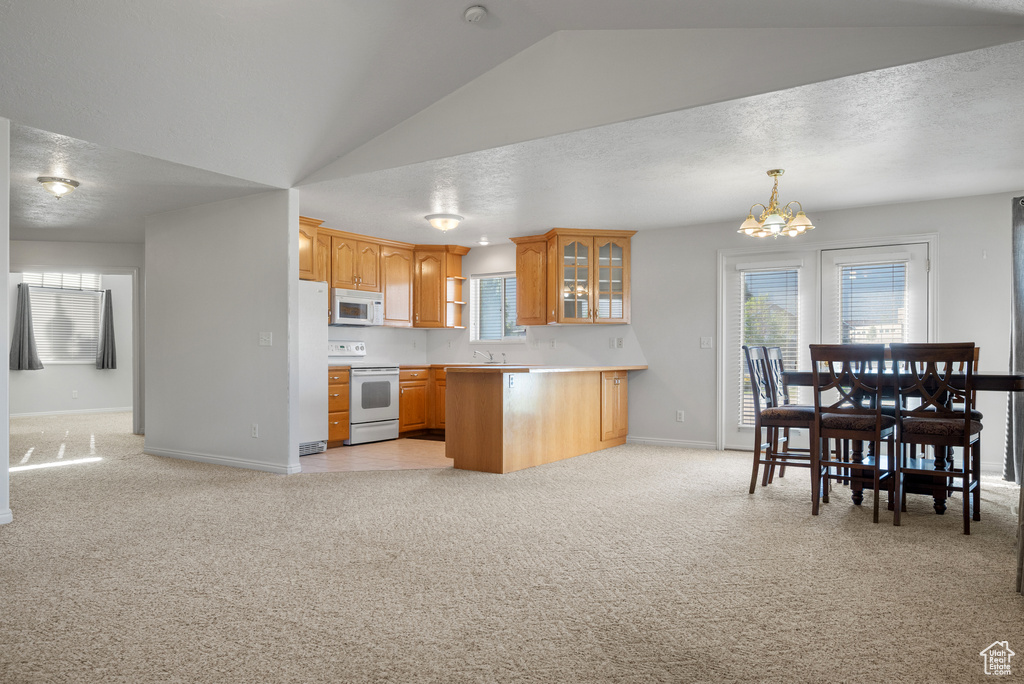 Kitchen featuring white appliances, light carpet, glass insert cabinets, a chandelier, and vaulted ceiling