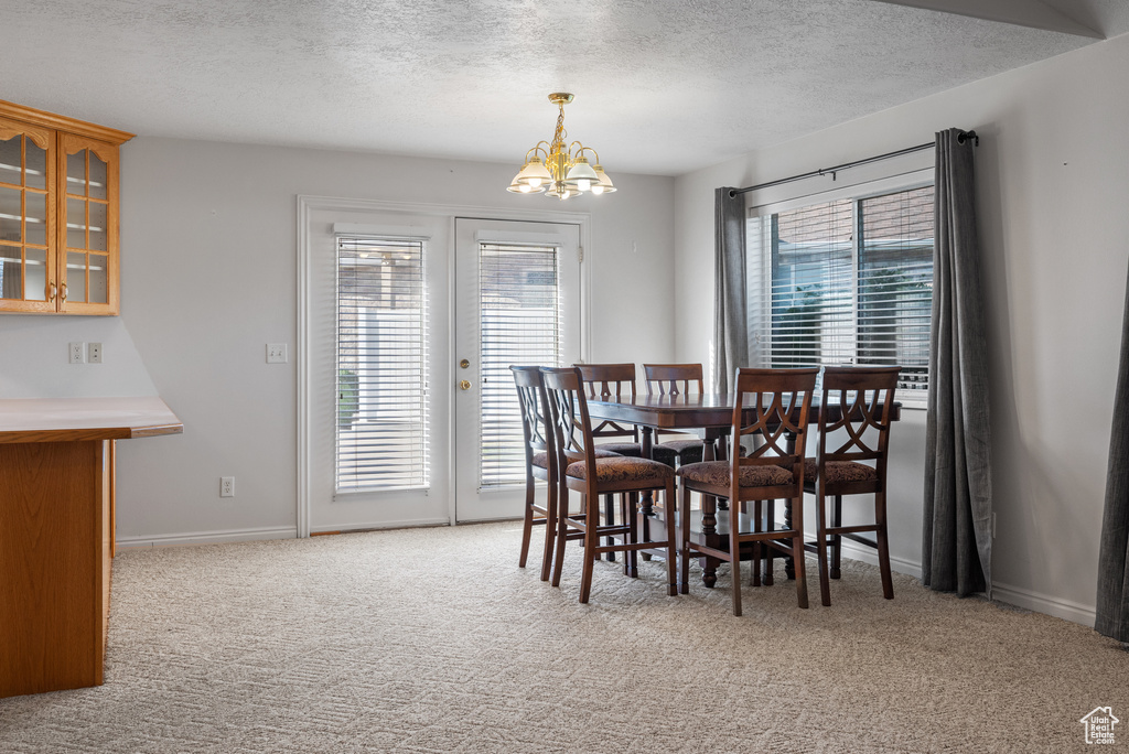 Dining space with a textured ceiling, a chandelier, and carpet