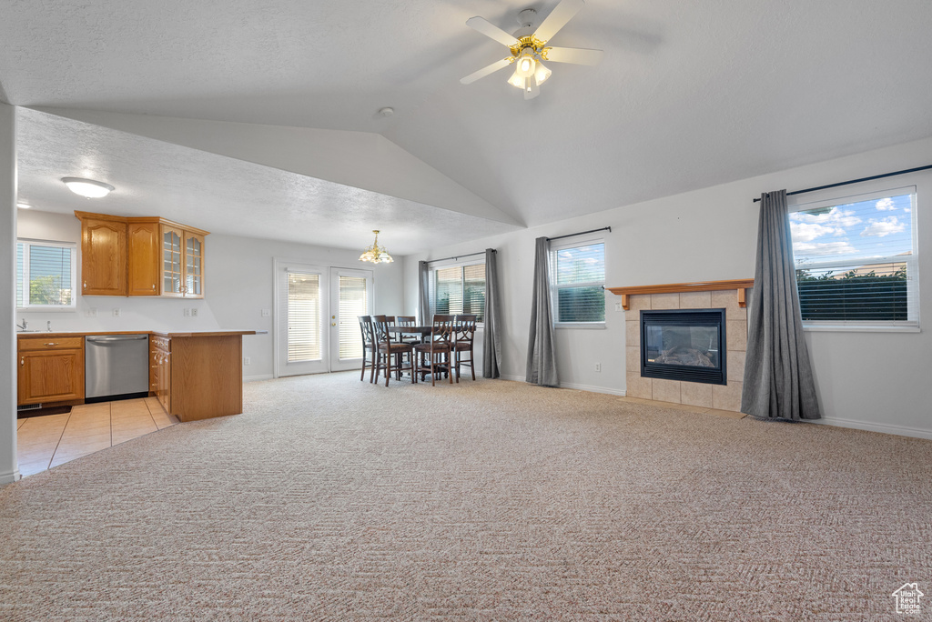 Living room with lofted ceiling, plenty of natural light, a ceiling fan, light colored carpet, and a textured ceiling