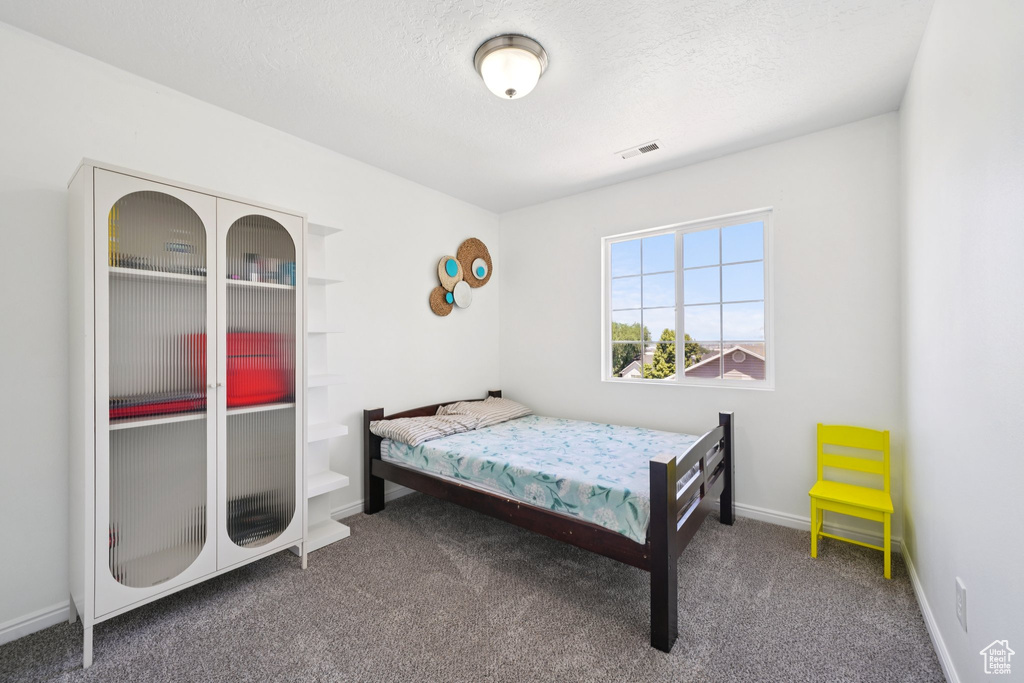 Carpeted bedroom with a textured ceiling and baseboards