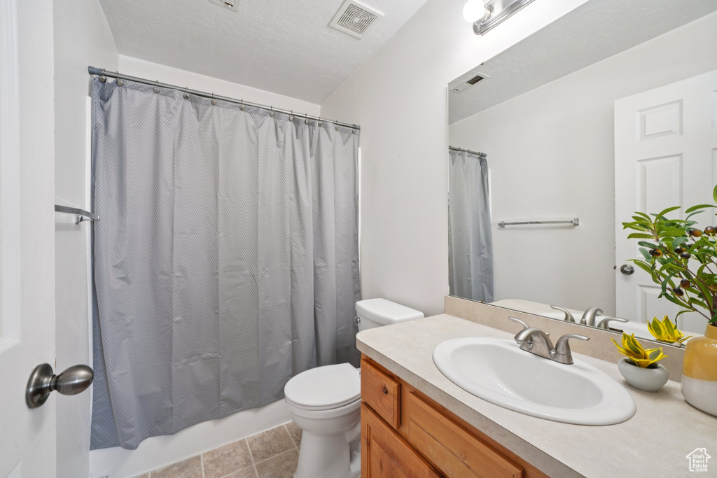 Bathroom with vanity, shower / bath combo, and tile patterned flooring