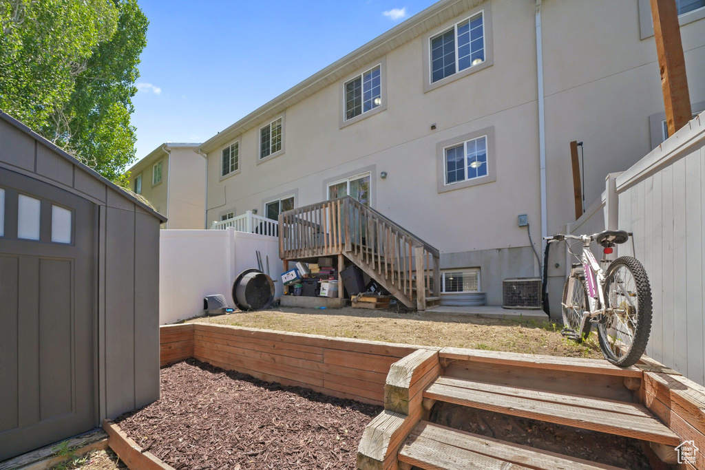 Rear view of house featuring stucco siding and a storage unit