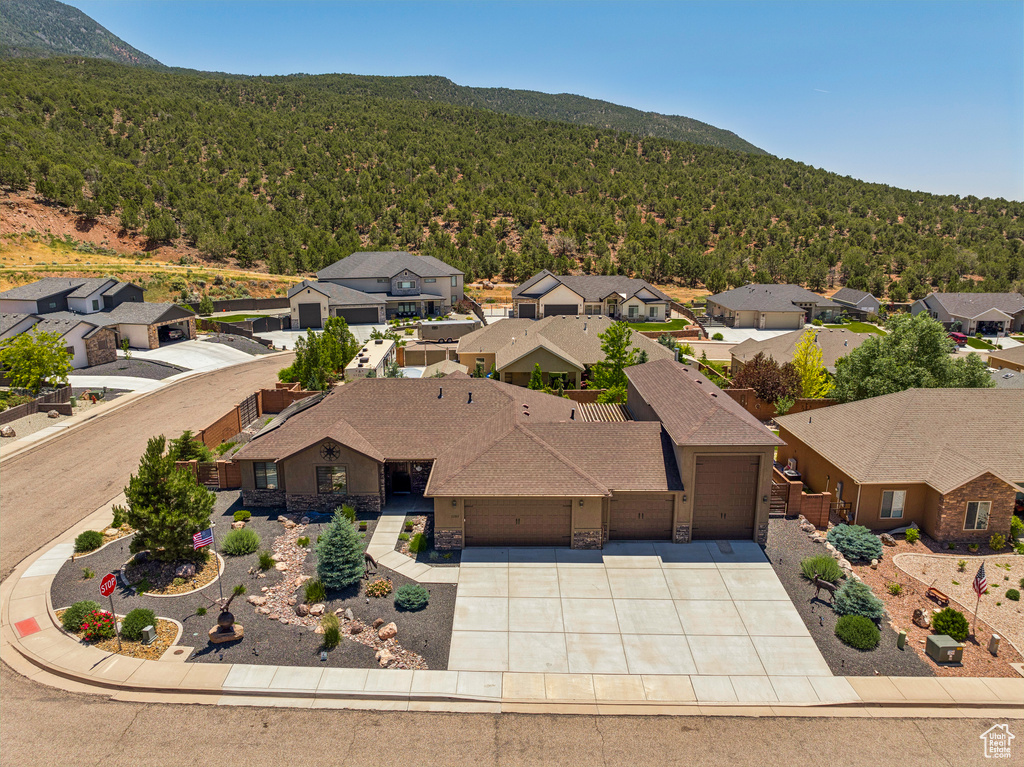 Aerial view of residential area featuring a heavily wooded area and a mountain backdrop