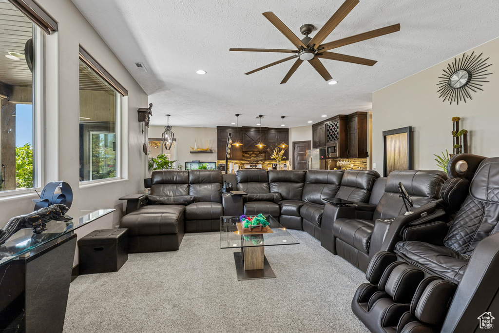 Carpeted living room featuring a ceiling fan, a textured ceiling, and recessed lighting
