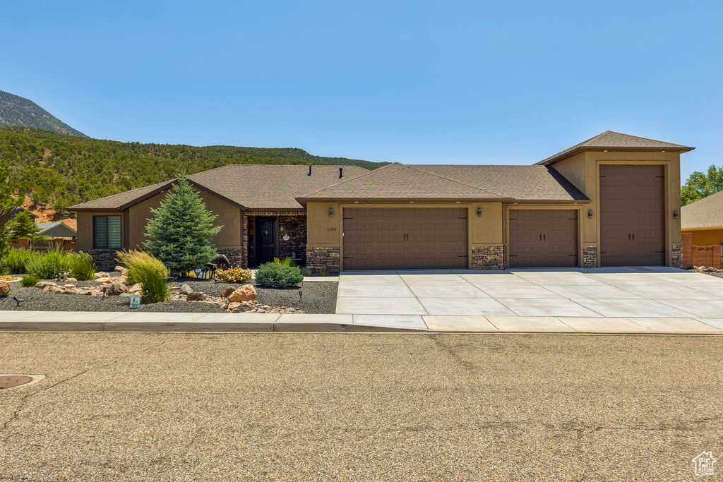 View of front of house with a garage, stone siding, concrete driveway, and a mountain view
