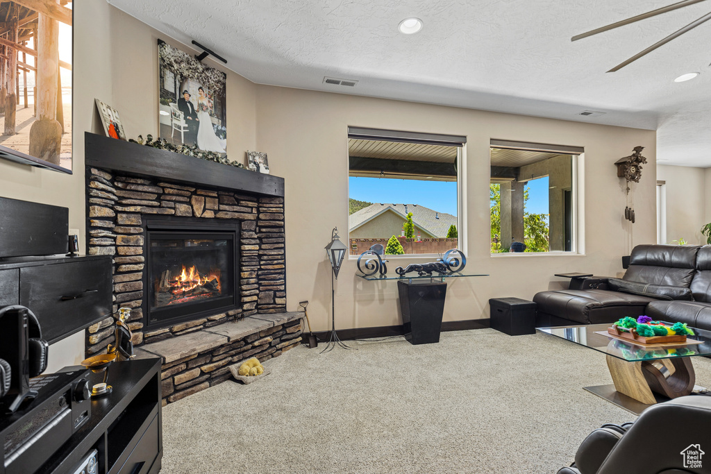 Carpeted living area featuring a fireplace, recessed lighting, ceiling fan, and a textured ceiling