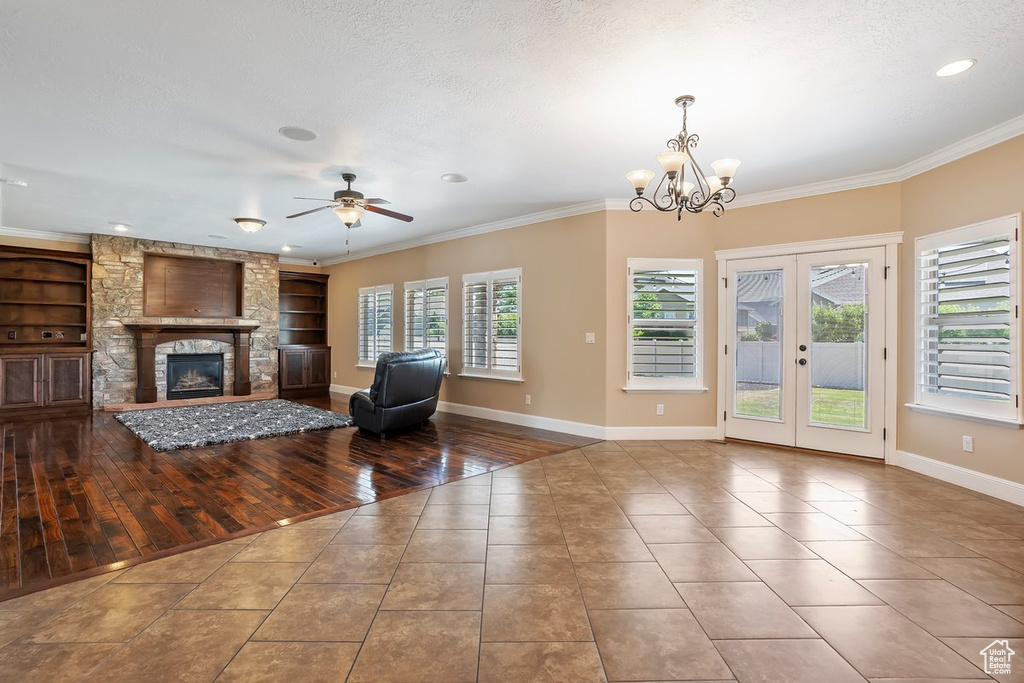 Living room featuring tile patterned floors, ornamental molding, a ceiling fan, a fireplace, and built in shelves