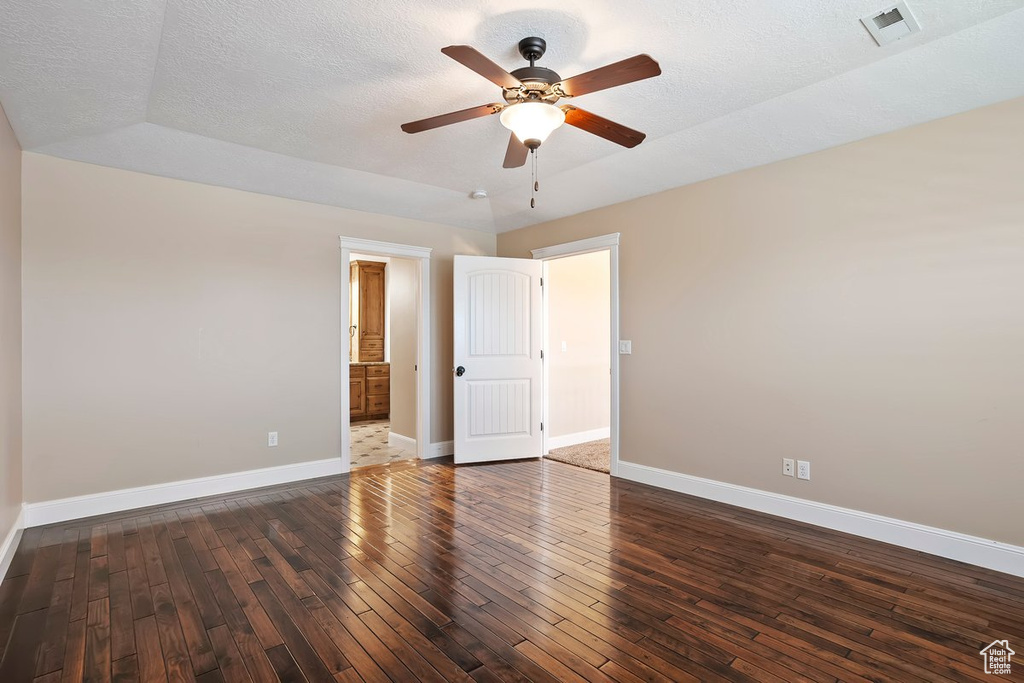 Empty room with dark wood-type flooring, ceiling fan, and a textured ceiling