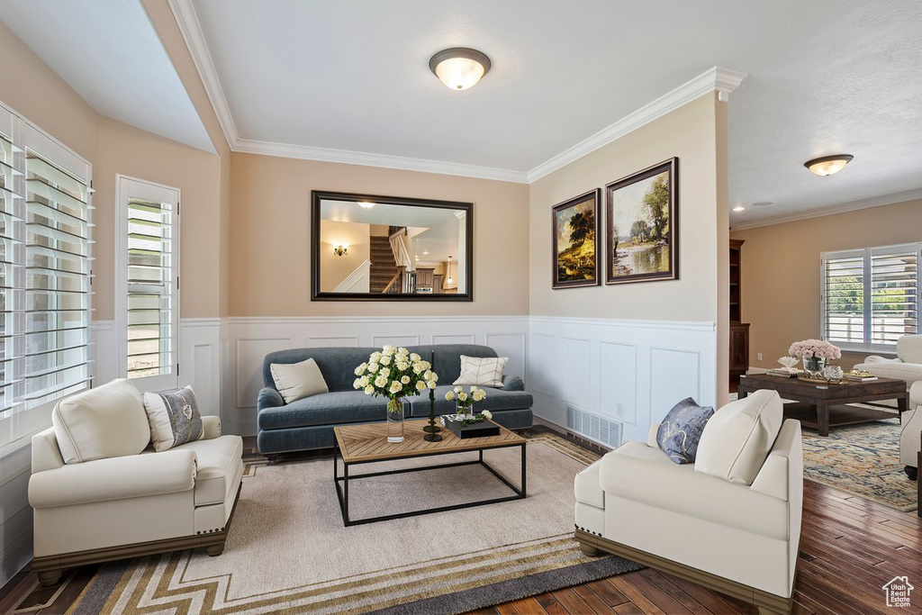 Living room featuring ornamental molding, wood finished floors, and a wainscoted wall