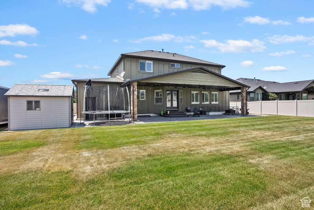 Back of house with a patio area, a trampoline, board and batten siding, an outdoor structure, and entry steps