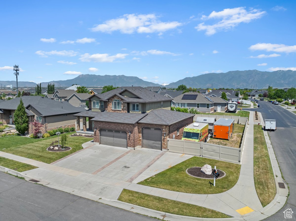 View of front of property featuring an attached garage, a residential view, brick siding, and a mountain view