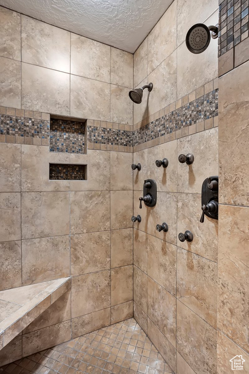 Bathroom featuring tiled shower and a textured ceiling