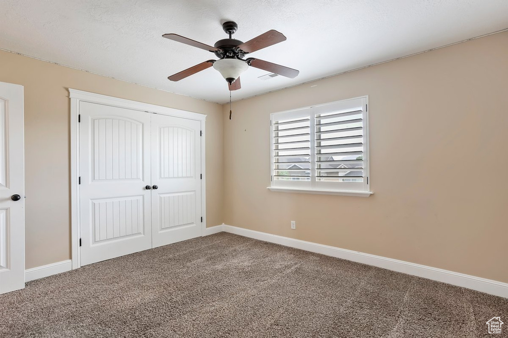 Unfurnished bedroom with carpet, a closet, and ceiling fan