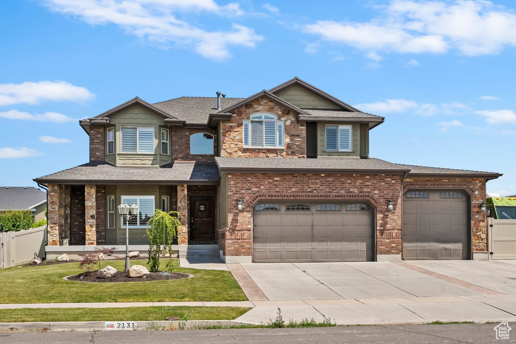 View of front facade featuring concrete driveway, an attached garage, a shingled roof, brick siding, and stone siding