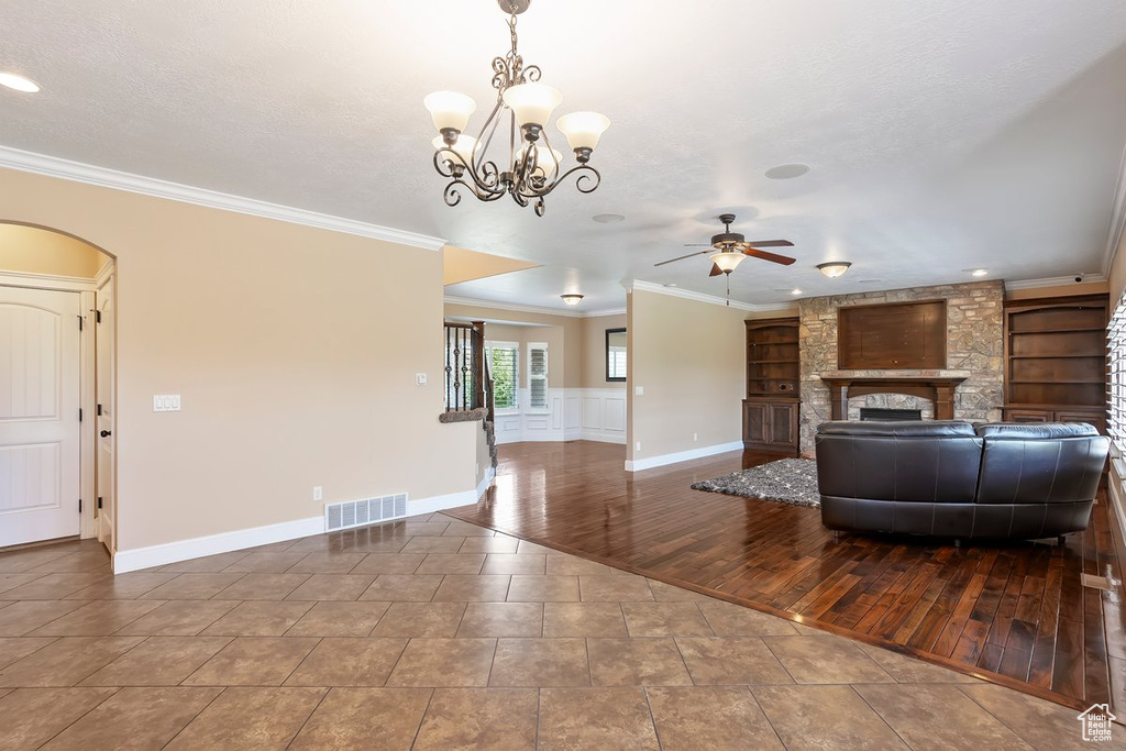 Living room featuring ceiling fan, a fireplace, ornamental molding, a chandelier, and built in features