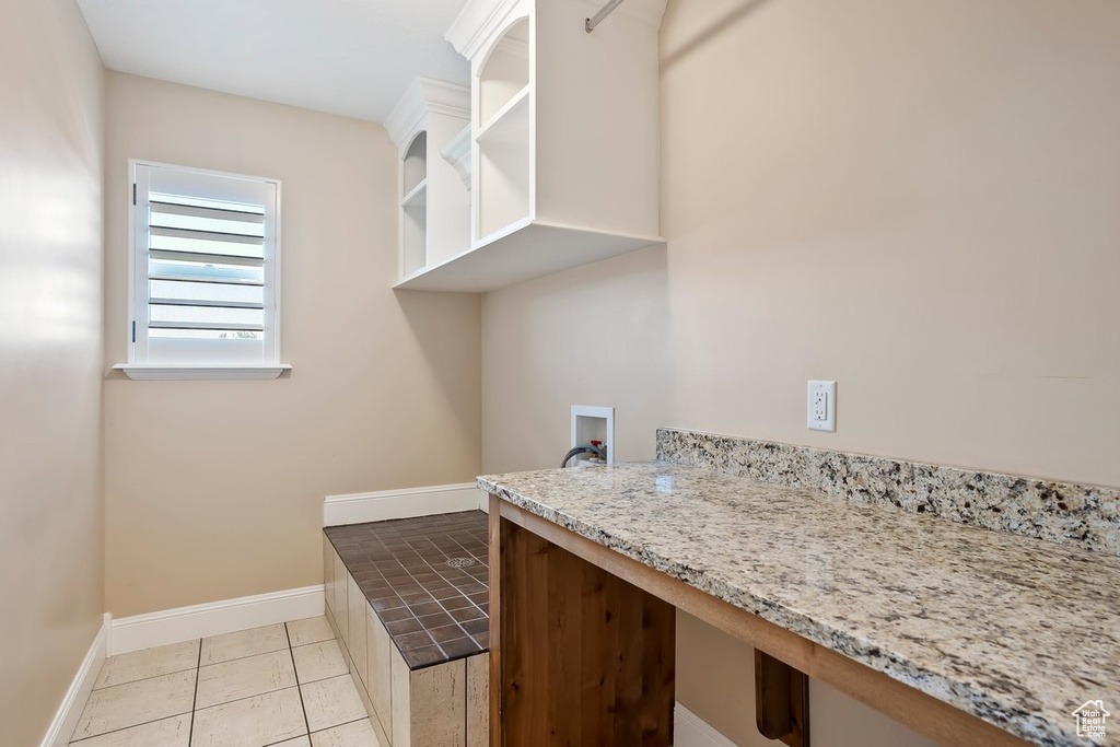 Laundry room with washer hookup, light tile patterned flooring, and a desk