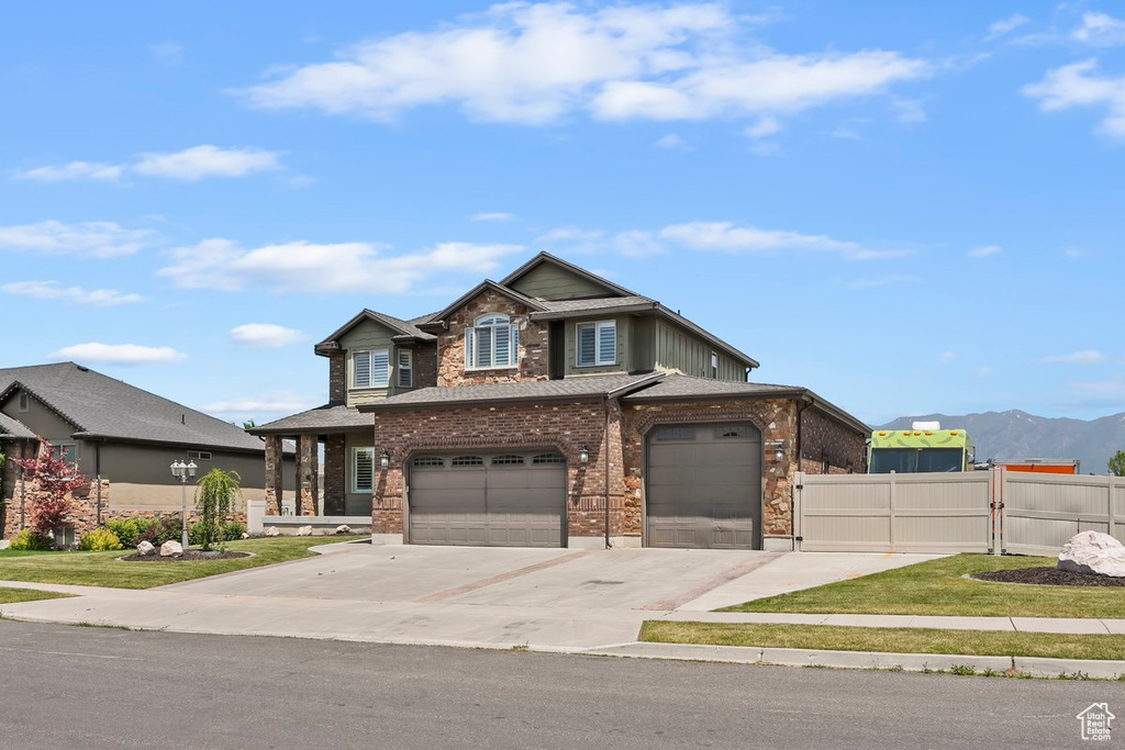 View of front of house featuring concrete driveway, brick siding, a garage, and a mountain view