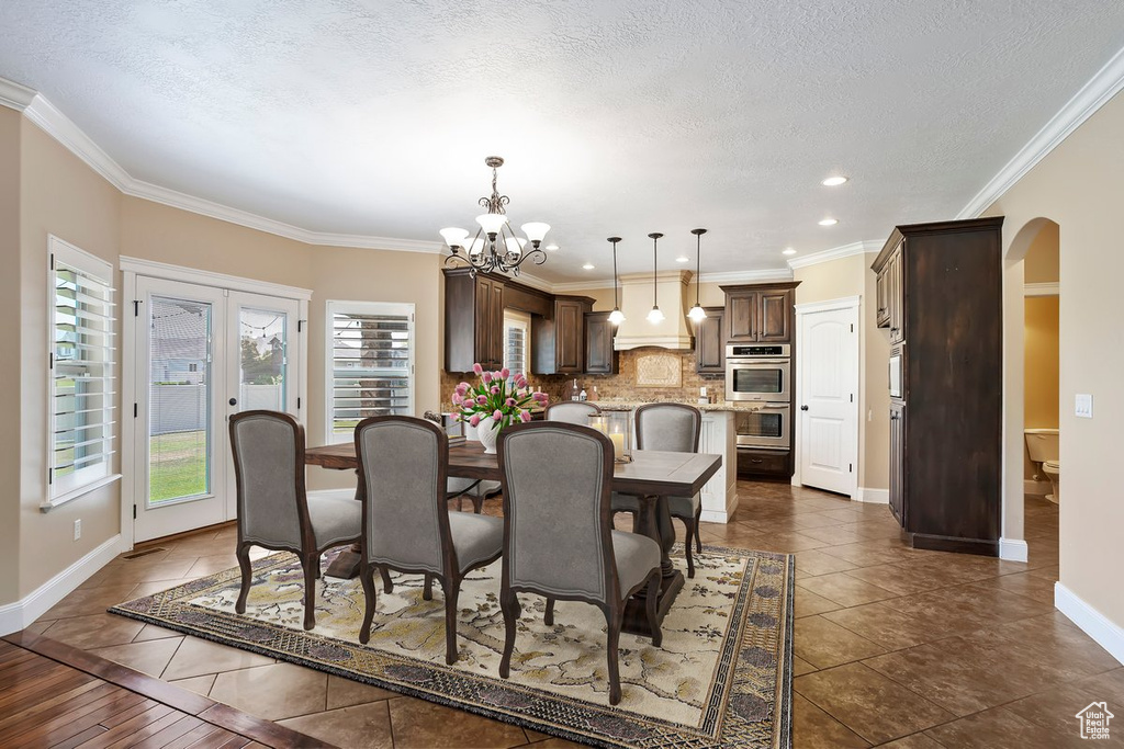 Dining area with arched walkways, a chandelier, recessed lighting, dark tile patterned floors, and a textured ceiling