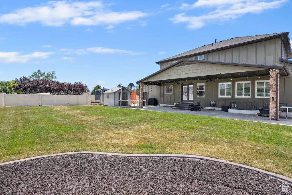Rear view of house featuring board and batten siding, a patio area, a shed, a fenced backyard, and entry steps