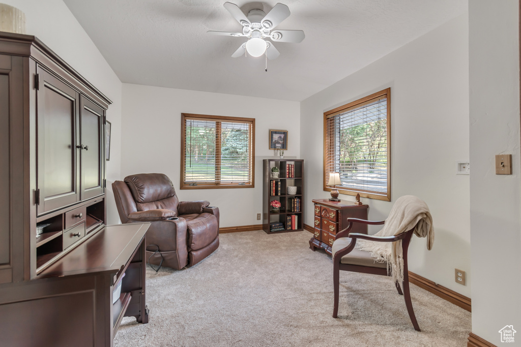 Living area with plenty of natural light, light carpet, and a ceiling fan