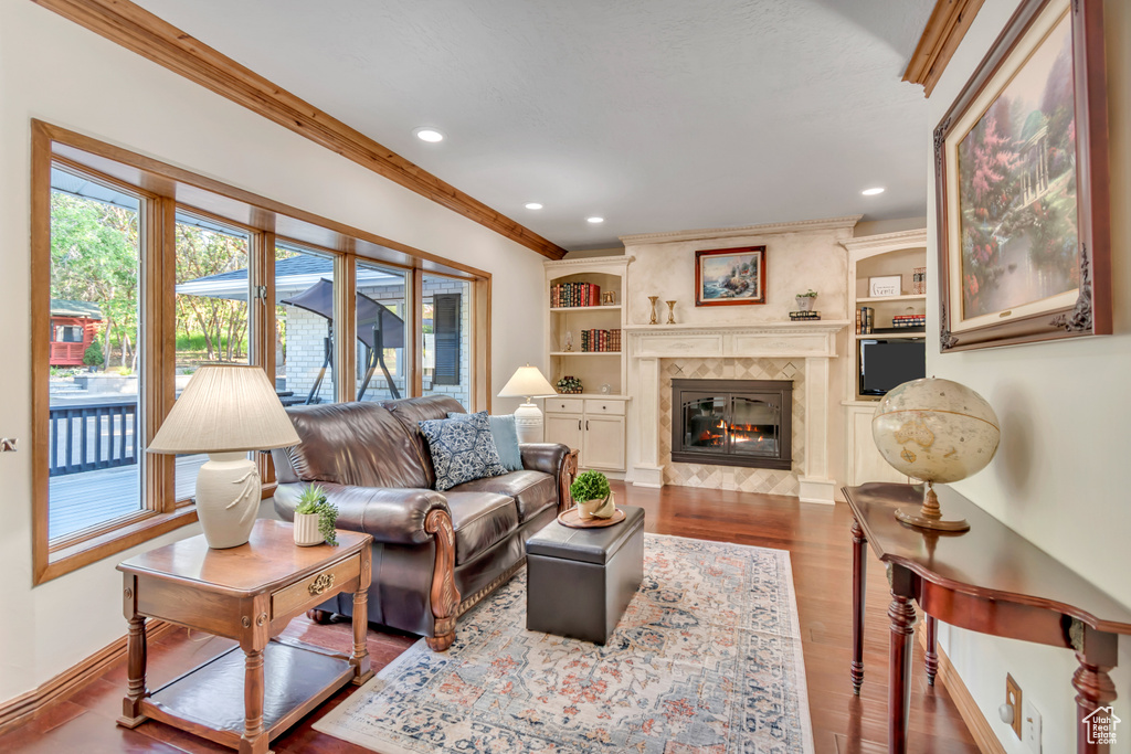 Living room featuring healthy amount of natural light, recessed lighting, wood finished floors, a fireplace, and ornamental molding