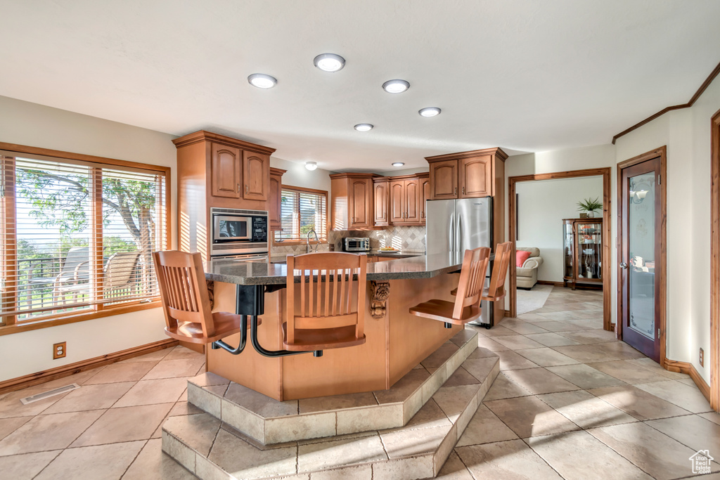 Kitchen with stainless steel appliances, tasteful backsplash, a kitchen bar, a kitchen island, and recessed lighting