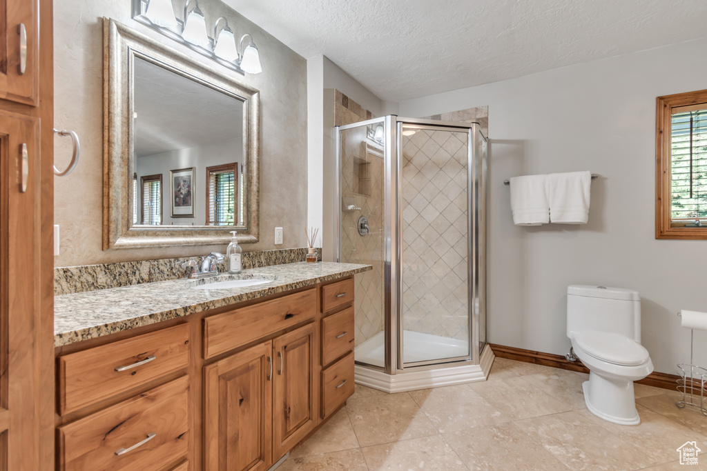 Bathroom featuring vanity, a shower stall, tile patterned flooring, and a textured ceiling