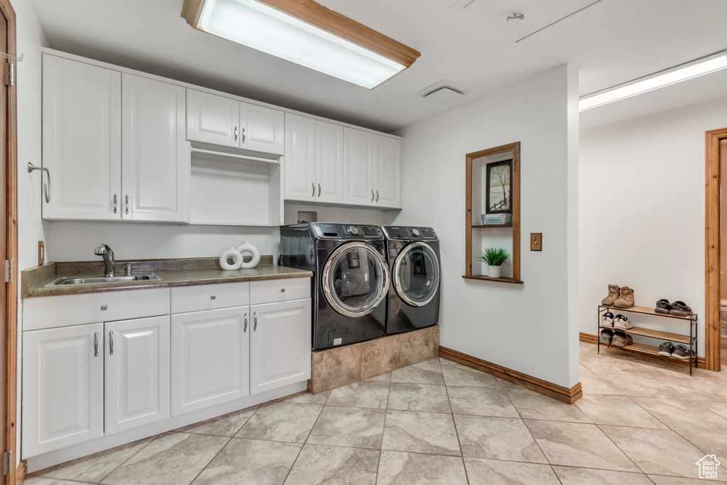 Laundry area with cabinet space, separate washer and dryer, and light tile patterned flooring