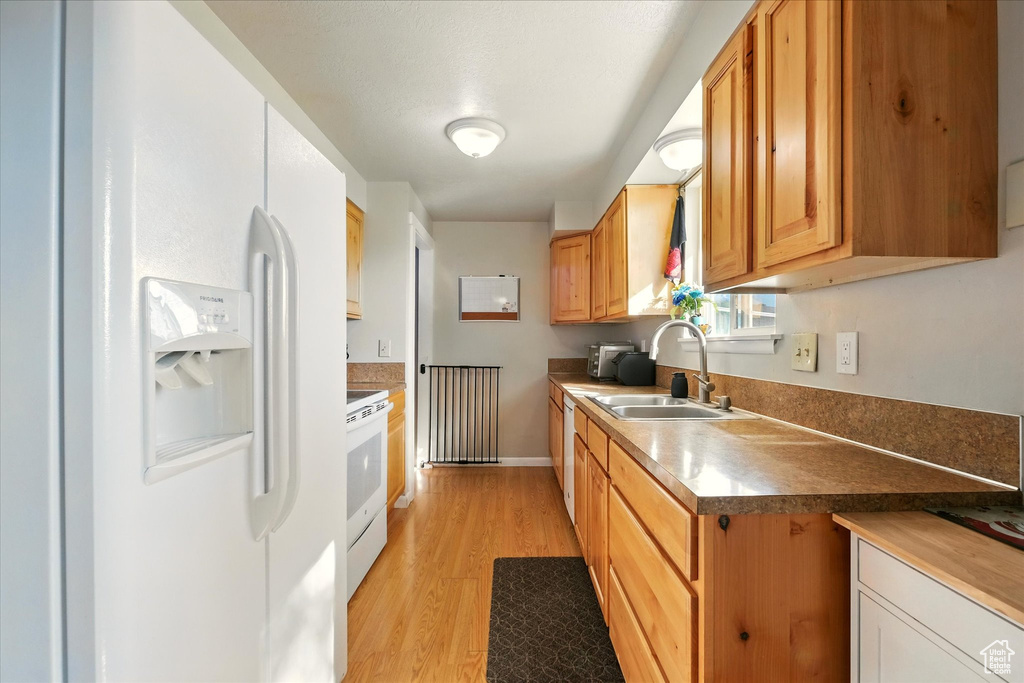 Kitchen with white appliances and light wood-style flooring