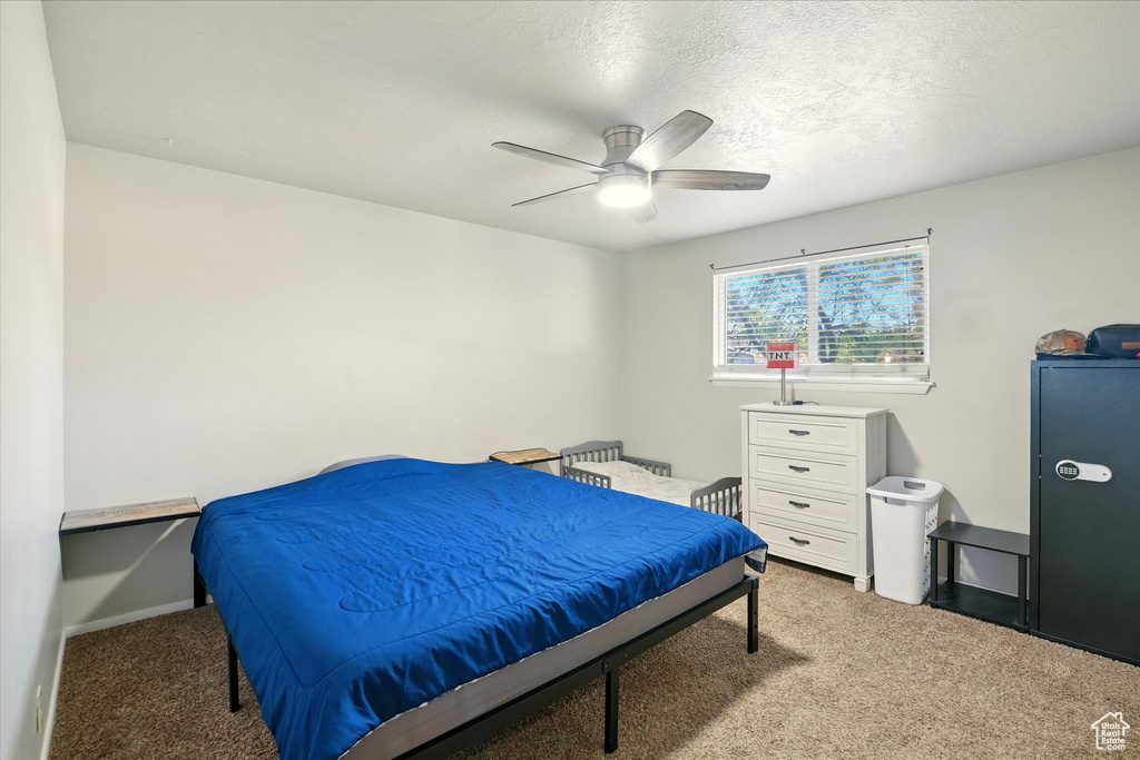 Carpeted bedroom featuring ceiling fan and a textured ceiling