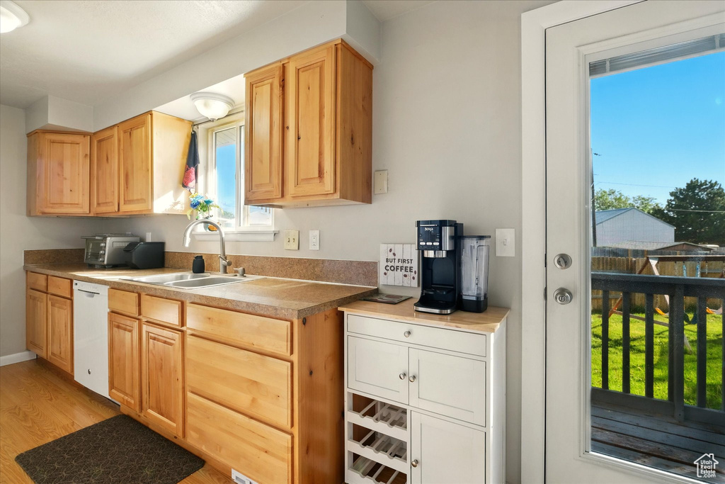 Kitchen with white dishwasher, light wood finished floors, and light brown cabinets