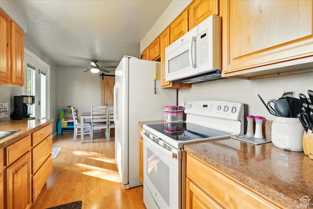 Kitchen featuring white appliances, light wood-type flooring, and ceiling fan