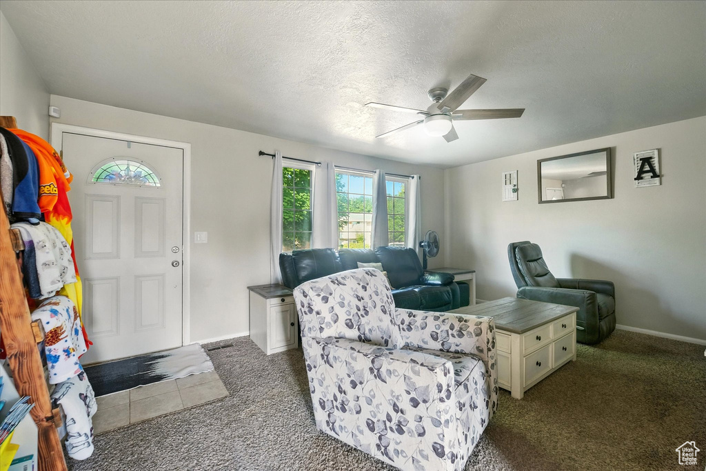 Entrance foyer with dark carpet, ceiling fan, and a textured ceiling