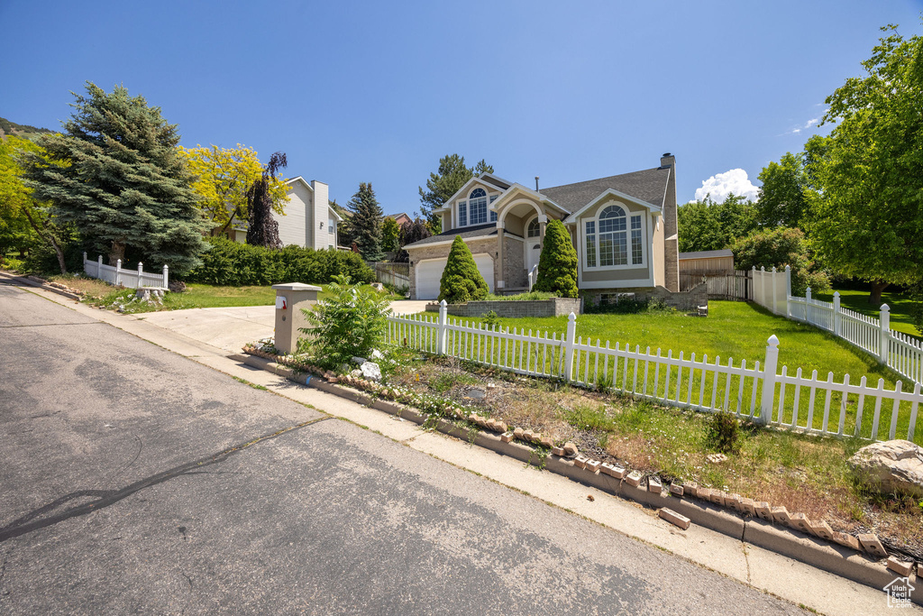 View of front of property with driveway, a fenced front yard, and a chimney